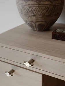 Modern wooden furniture featuring minimalist handles and a vase with geometric patterns on a light-colored wooden surface.