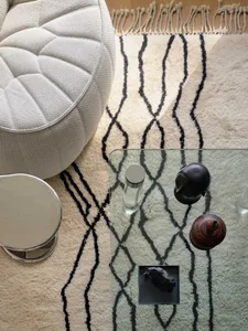 A modern living room featuring a glass side table with a glass vase, wooden sculpture, and glass jar.