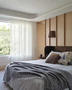 A modern minimalist bedroom with a textured blanket, pillows, and a soft, neutral color palette.