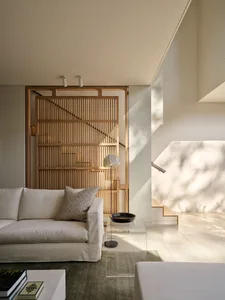A modern minimalist living room featuring a ceiling light fixture, a white sofa, and a glass coffee table.