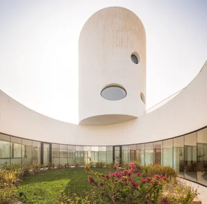 A modern residential interior with a circular concrete structure and a central courtyard.
