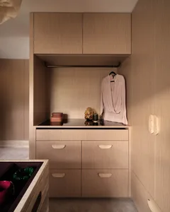 A modern walk-in wardrobe with wooden storage units and a hanging rail for clothing.