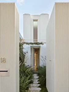 A minimalist house with a white brick facade and tall window.