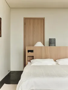 Minimalist bedroom featuring a wooden bed with a wooden headboard and white bedding.