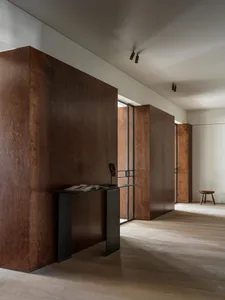 Modern minimalist entrance with dark wooden walls and a sleek black table.