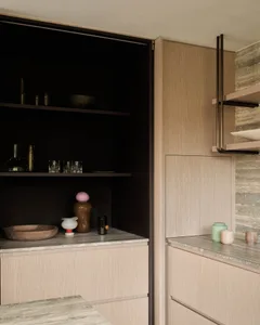 A minimalist residential kitchen with light wood cabinets and shelves.