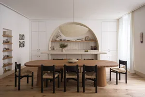 Modern minimalist kitchen with a stone table and wooden chairs.