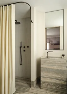 Modern bathroom with marble floor, sink, and shower area enclosed by a beige curtain.