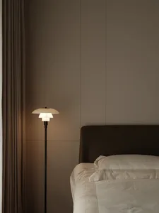 A minimalist bedroom with modern design features, showcasing a sleek floor lamp and a comfortable bed with minimalistic beddi
