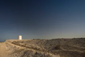 A modern architectural structure amidst a desert landscape with sandy terrain.