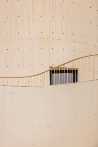 Modern building exterior made of concrete with a curved railing.