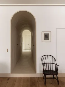 A modern interior hallway with arched doorways made of concrete.