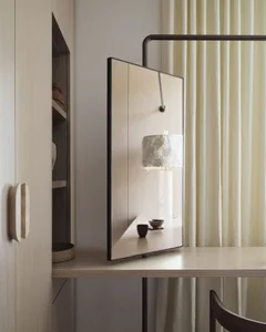 Modern home office with a wooden desk, lamp, and curtain.