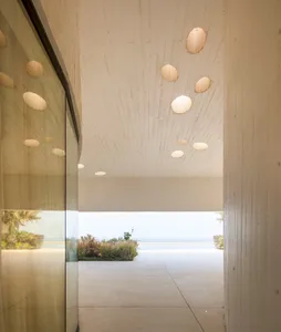 A modern interior design featuring a concrete entrance hall with ocean views and spherical light fixtures.
