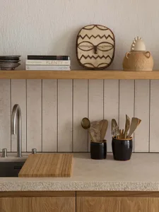 A modern kitchen with wooden cabinets, a ceramic vase, and a cutting board.