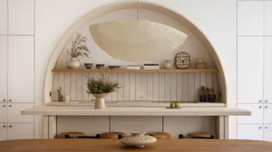 A modern kitchen with wooden cabinets, a stone countertop, and decorative items on a shelf.