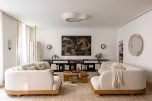 Modern living room with neutral colors, featuring two sofas adorned with pillows and a wooden coffee table, against a backdro