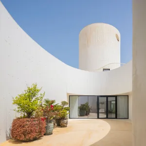 Modern, white architectural interior with concrete walls, open space, and glass doors.