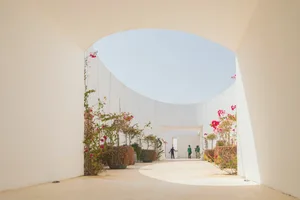 A modern white concrete interior with open archways and plants.