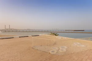 A sand-covered balcony overlooking the sea with a railing and a few circular platforms.