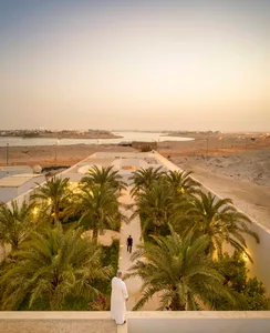 Concrete structures surrounded by palm trees during dusk.