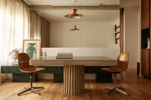 A minimalist living room with a concrete table and brown chairs.