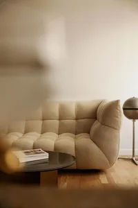 A minimalist living room featuring a comfortable beige fabric sofa, a round coffee table with a stack of books, and a globe-s