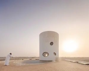 Minimalist observatory building with white concrete exterior and circular windows.