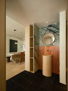 Modern bathroom featuring marble walls and a cylindrical pedestal sink.