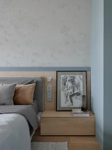 Modern bedroom with wooden furniture, a grey upholstered bed, and a framed artwork on the wall.