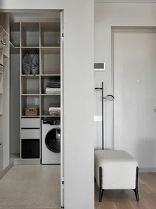 A modern closet laundry room featuring a white column and a wooden floor.