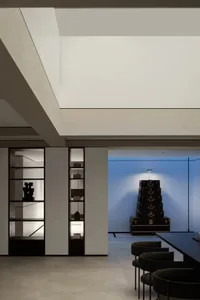 A modern home office with minimalist design featuring a black desk and chairs, and a stack of suitcases acting as a decorativ
