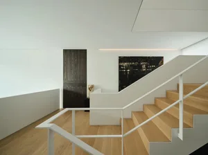 Modern minimalist interior with a wooden staircase and white walls.