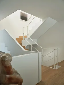 Modern interior design featuring white stairs with wooden steps, white walls, and a minimalist aesthetic.
