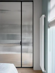 Minimalist bedroom featuring frosted glass panels and white radiator.