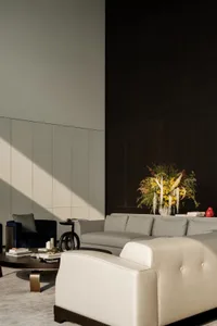 A modern living room with neutral textiles, including a beige sofa, dark armchair, and a wooden coffee table.