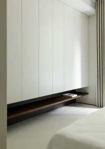 A minimalist bedroom with floating wooden shelves and white walls.