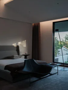 A minimalist bedroom with a gray fabric bed and a modern lounge chair.