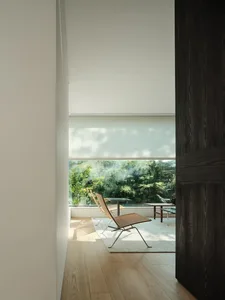 A minimalist living room with glass window blinds and wooden flooring.