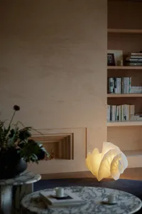 A minimalist living room featuring a uniquely designed paper table lamp emitting a warm glow.