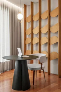 A minimalist office space featuring a black table with a laptop, a white chair, and a wooden wall with geometric shapes.