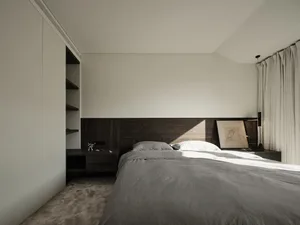 A minimalist bedroom featuring a wooden bed frame, grey bedding, and a simple painting on the wall.