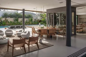 Contemporary residential interior space with open-plan living areas, a wine display, and a wooden dining table.