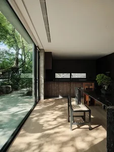 現代住宅廚房，搭配大理石檯面與木質櫥櫃，設有大型窗戶可眺望樹景