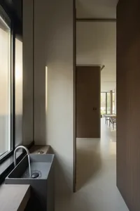 A minimalist bathroom features a concrete sink and a window with natural light.