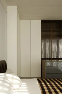 Well-organized minimalist bedroom with textured neutral-colored walls, white bedding, and brown and white striped rug.