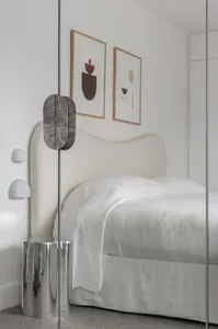 Modern minimalist bedroom featuring a upholstered bed headboard with marble accents and white bedding.