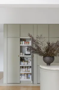 Minimalist green kitchen storage unit with pull-out drawers and shelves.