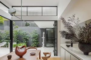 A modern dining room with wooden furniture, plants, and minimalist decor.