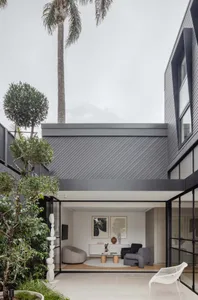 Modern, minimalist living room with concrete walls, sleek furniture, and large windows.